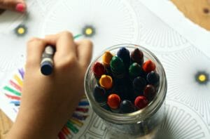 jar of crayons and child coloring