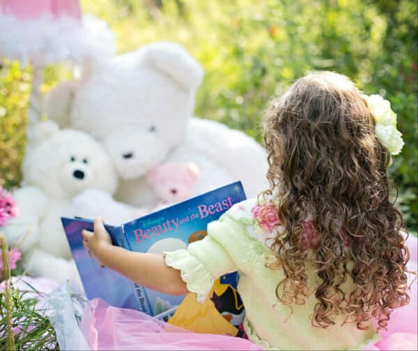 preschool girl reading to stuffed animals