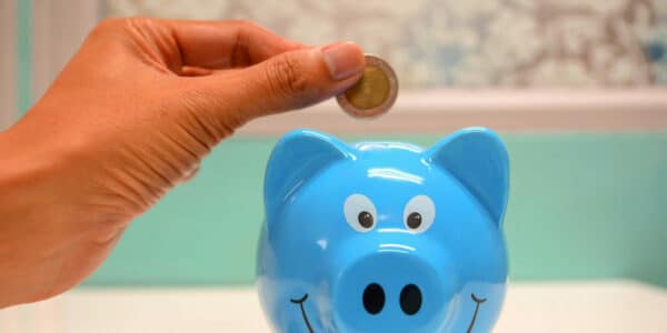 Hand putting a coin in a piggy bank