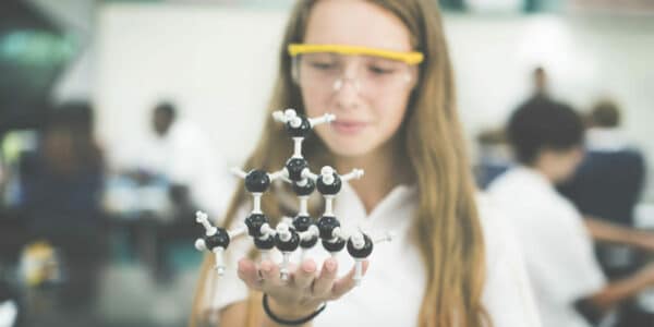 High school girl in science lab holding molecular model