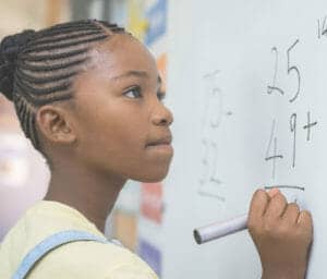 Young girl doing math problems on the whiteboard