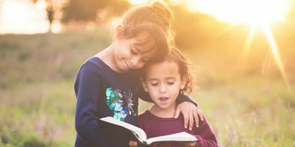2 young girls reading the Bible together
